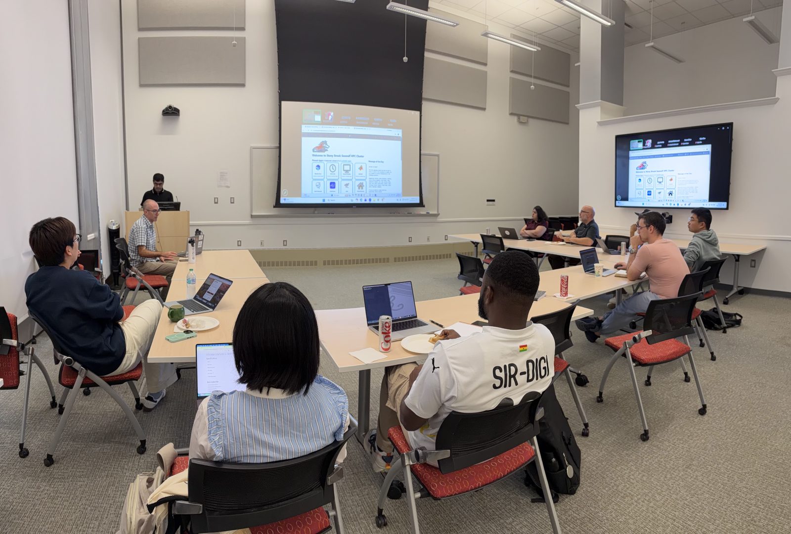 The IACS Seminar Room during the session, with attendees at laptops and the SeaWulf OnDemand dashboard on the projector and wall screen